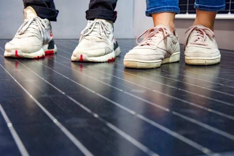 2 Personen stehen auf einem Solarmodul